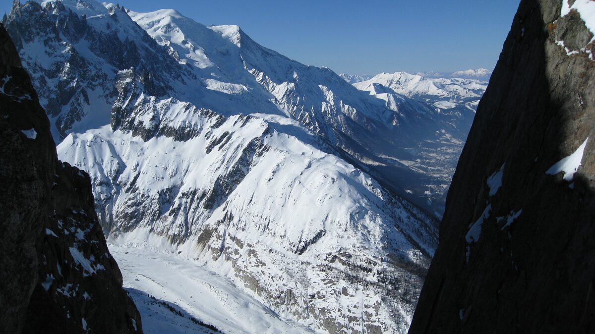 The Chamonix valley and the Mont Blanc massif under snow, seen between two rock walls from the Grands Montets