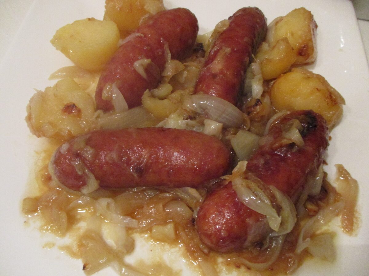 Savoy pork sausages browned in a pan with boiled potatoes and onions