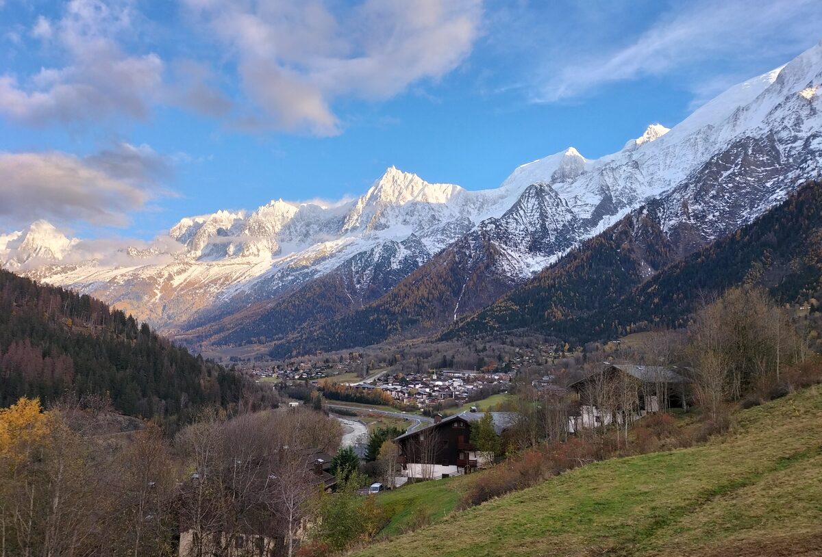 The village of Les Houches in the valley with the snow-capped Mont Blanc massif rising above it in evening light