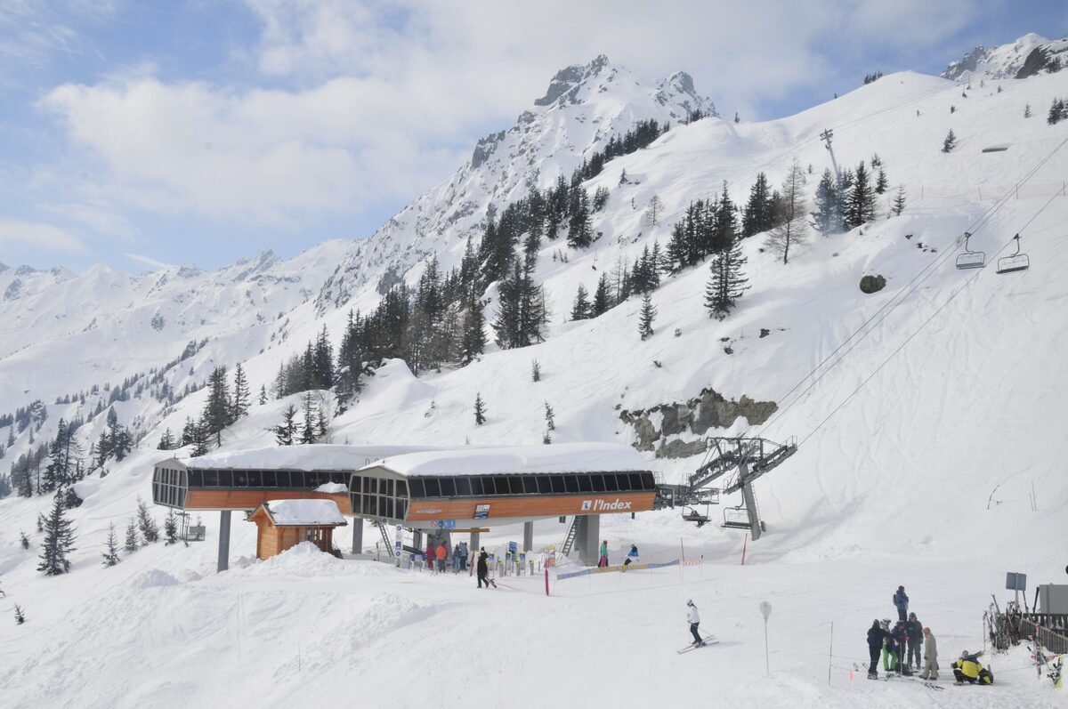 The La Flégère lift station and its chalet in deep snow, with skiers on the piste below