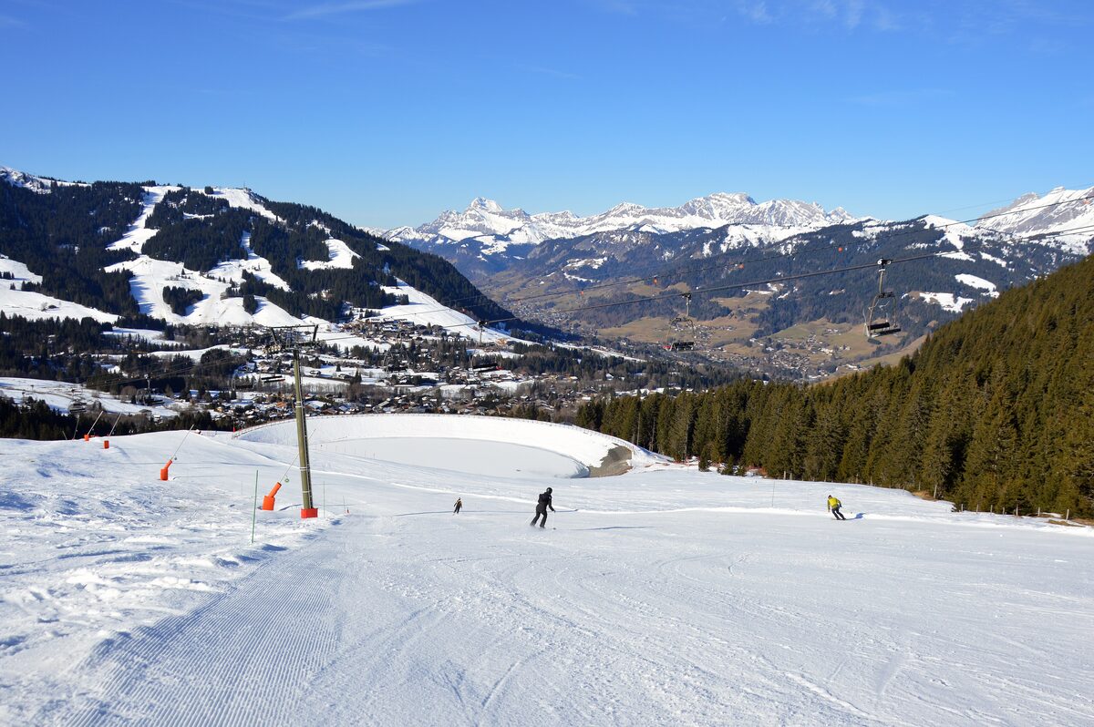Skiers on the Mandarines slope in Megève, with snowy hills and mountains behind