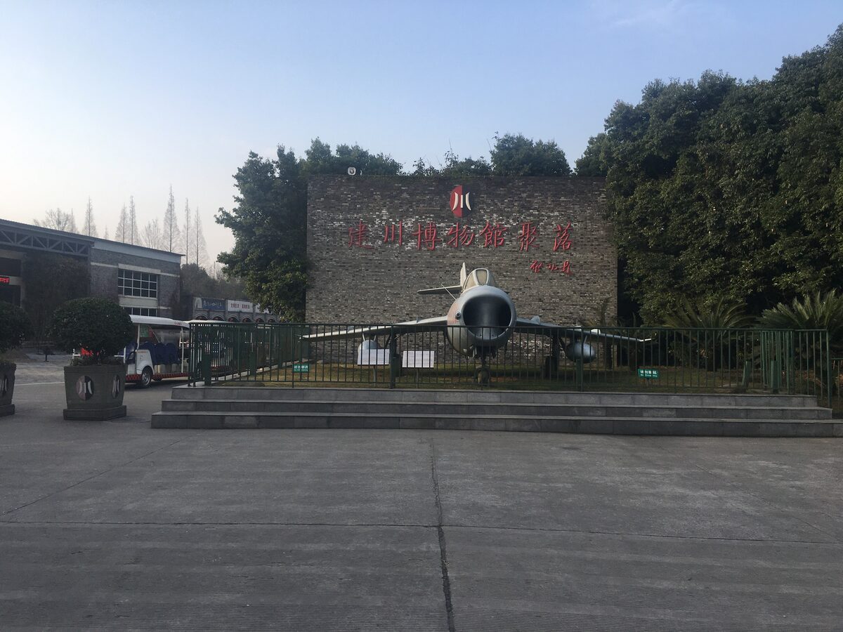 The brick entrance wall of the Jianchuan Museum Cluster in Anren with its red lettering, and a fighter jet on display in front