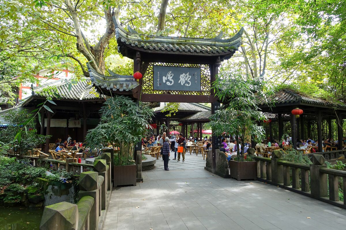 The Heming Teahouse entrance gate in People's Park, with bamboo chairs and tea drinkers under the trees