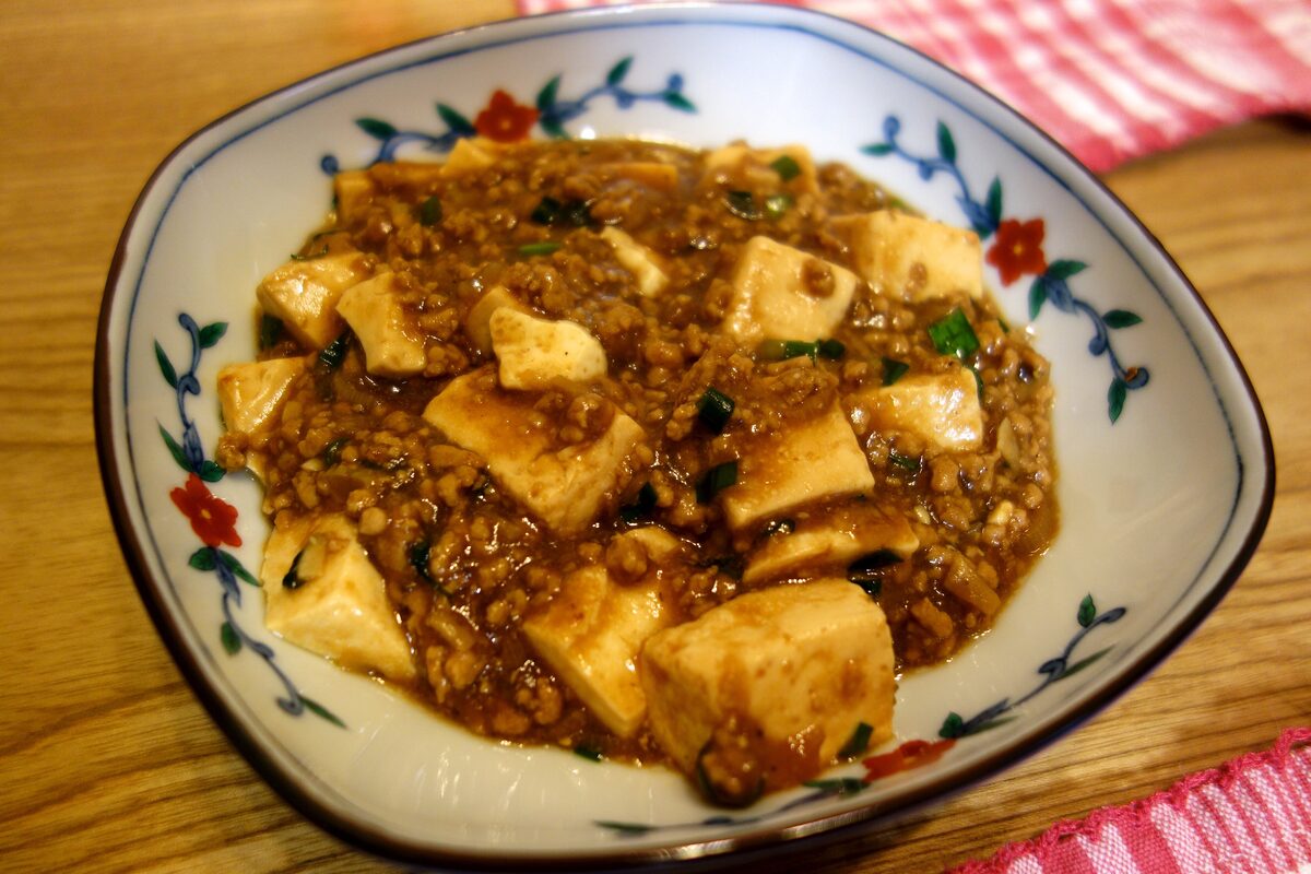 A plate of mapo tofu, soft tofu cubes in a brown chili-bean sauce with minced meat