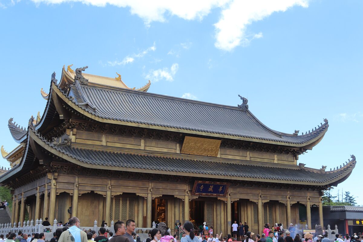 The golden-roofed Huazang Temple hall at the Golden Summit of Mount Emei, with crowds in front