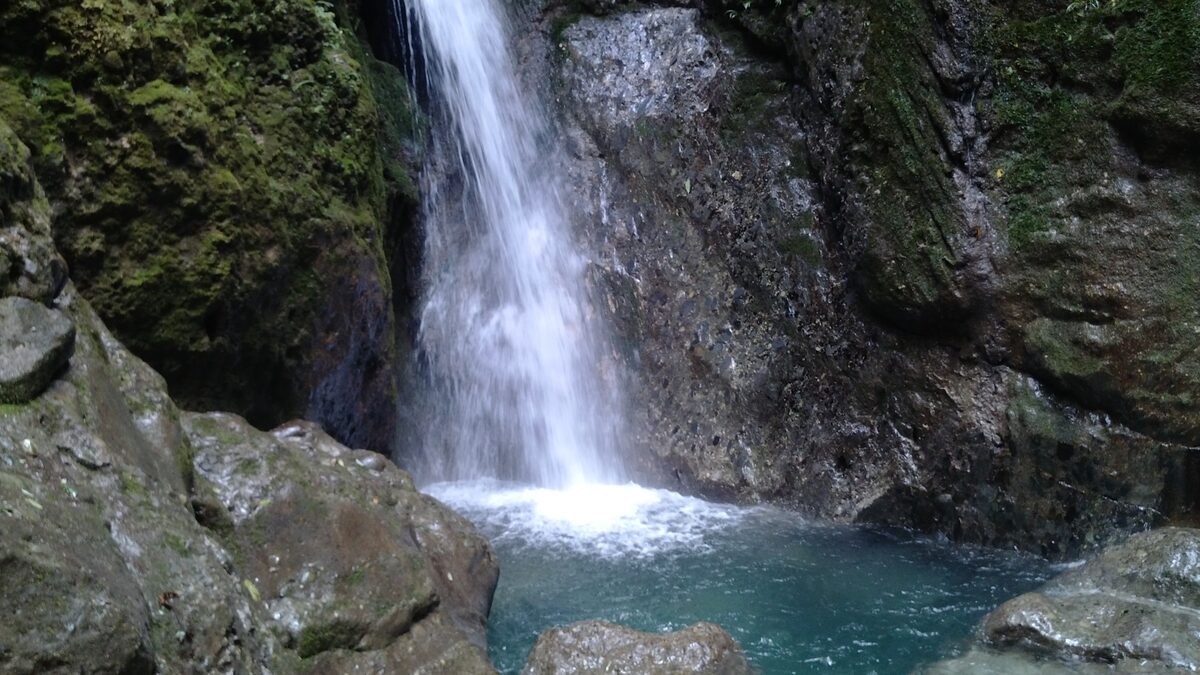 A waterfall dropping over mossy rock into a turquoise pool on the Back Mountain side of Mount Qingcheng