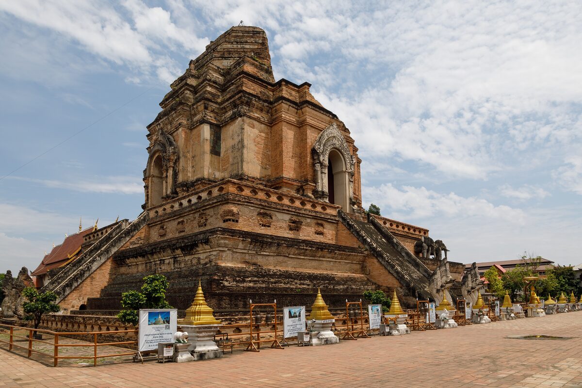 The ruined brick chedi of Wat Chedi Luang, with a stairway up its base and gilded stupas in front