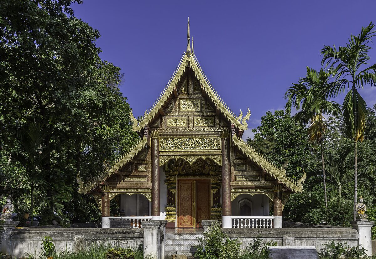 A gilded hall of Wat Chiang Man, set among palm trees on a green lawn