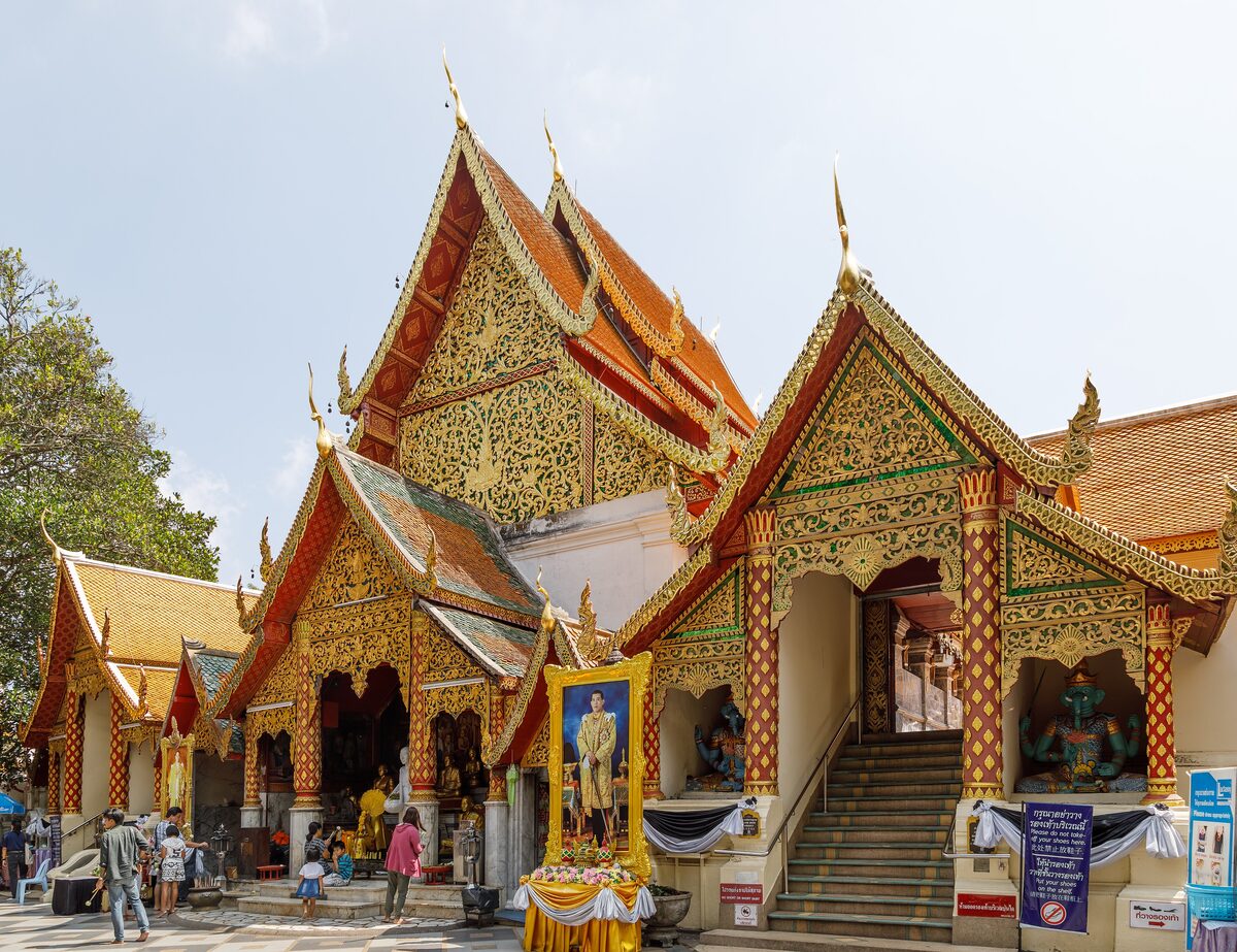 Gilded halls and a steep stairway at Wat Phra That Doi Suthep, with visitors at the entrance