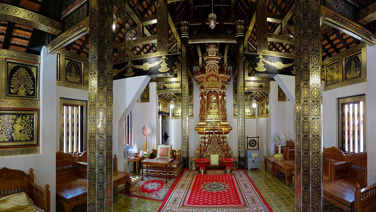 The gilded interior of a Lanna hall at Wat Phra That Lampang Luang, with a golden altar and red carpet