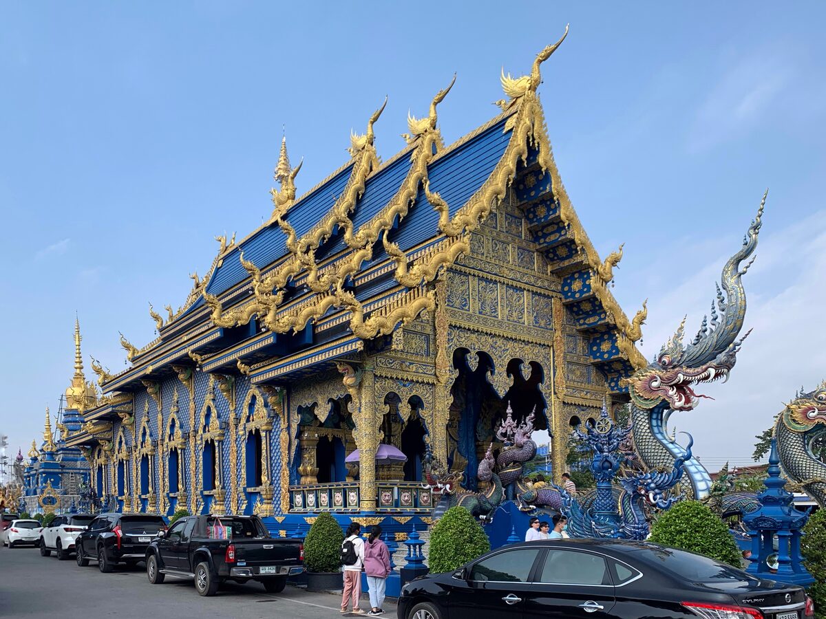The blue temple of Wat Rong Suea Ten, with gold trim and nagas along its roofline