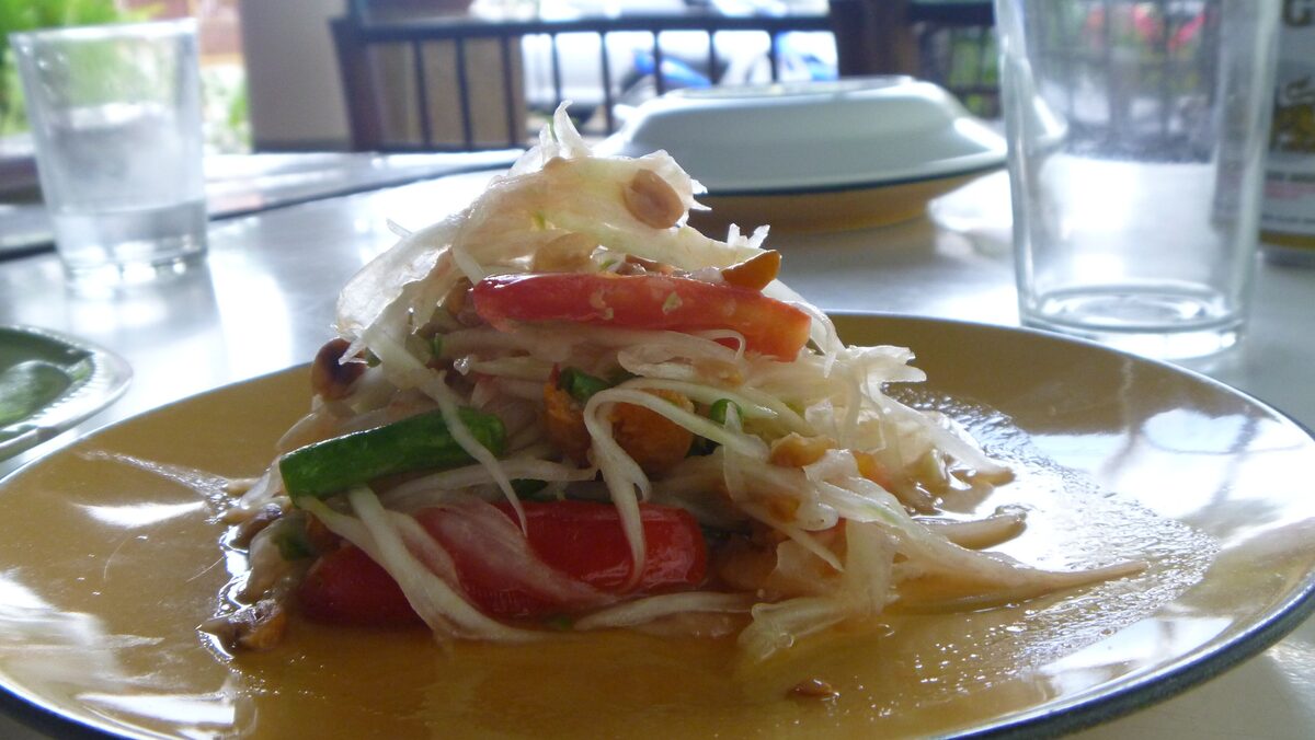 Green papaya salad with shredded papaya, tomato and peanuts on a plate