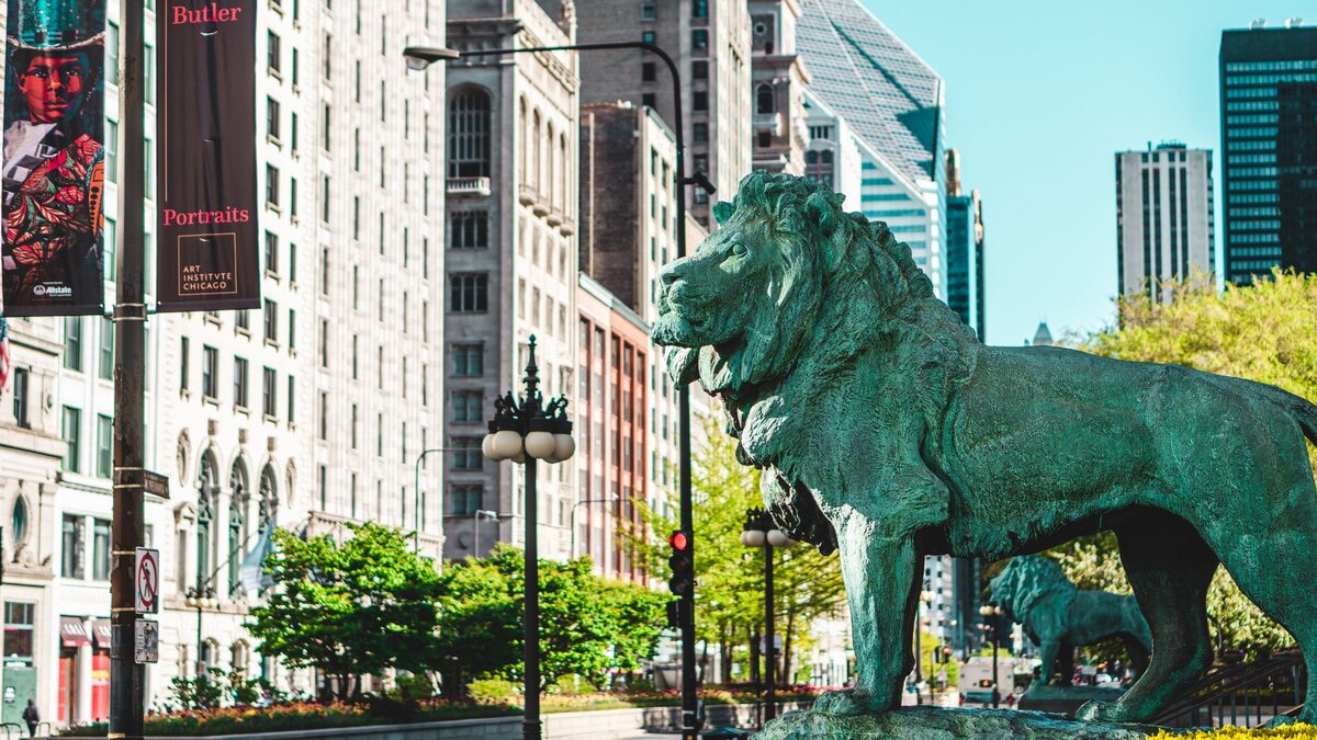 A bronze lion in front of the Art Institute of Chicago on Michigan Avenue, with skyscrapers beyond