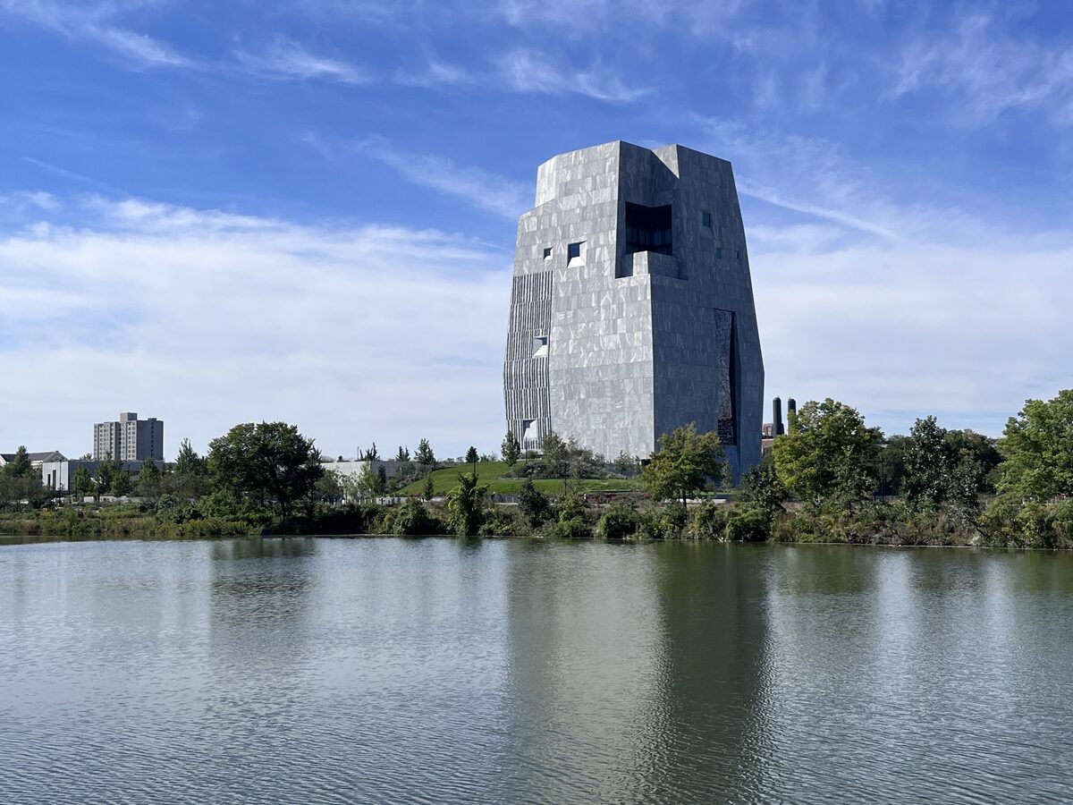 The granite Museum tower of the Obama Presidential Center rising over a lagoon in Jackson Park