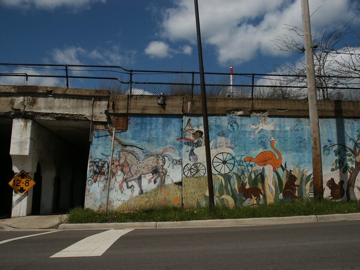 A mural of animals and bicycles along a railway embankment wall in Pilsen