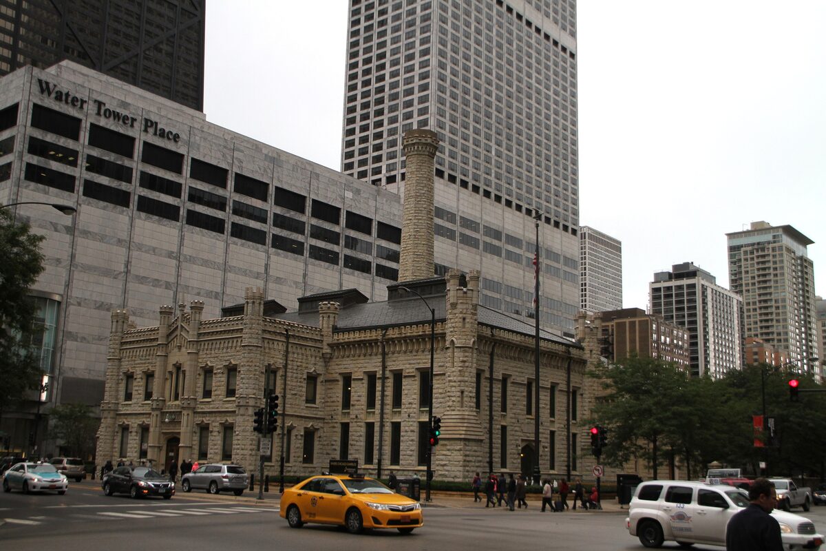 The Old Chicago Water Tower, a pale limestone castle, in front of tall modern buildings on Michigan Avenue