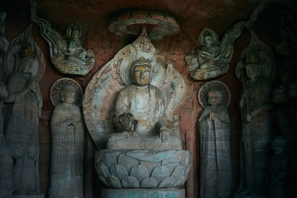 A seated Buddha with attendants and flying figures carved in a rock niche at Beishan, Dazu