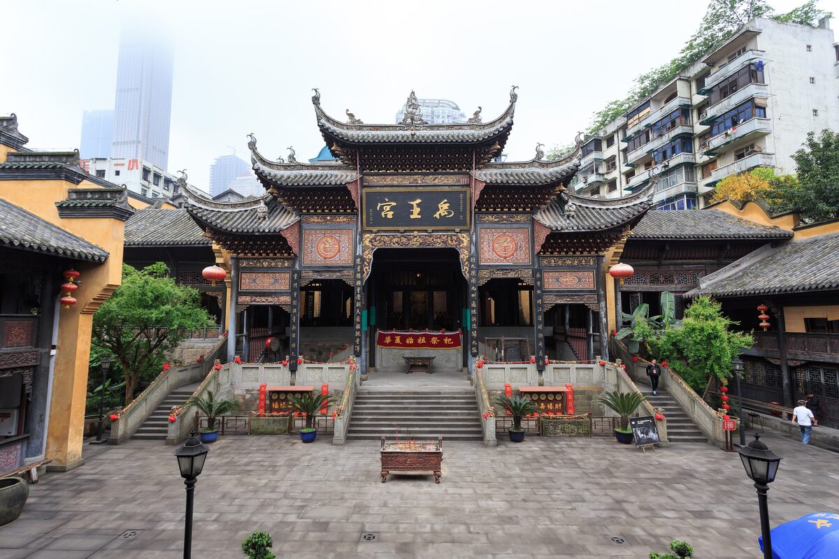 The ornate Yuwang Palace hall across a stone courtyard at Huguang Guild Hall, with a tower block behind