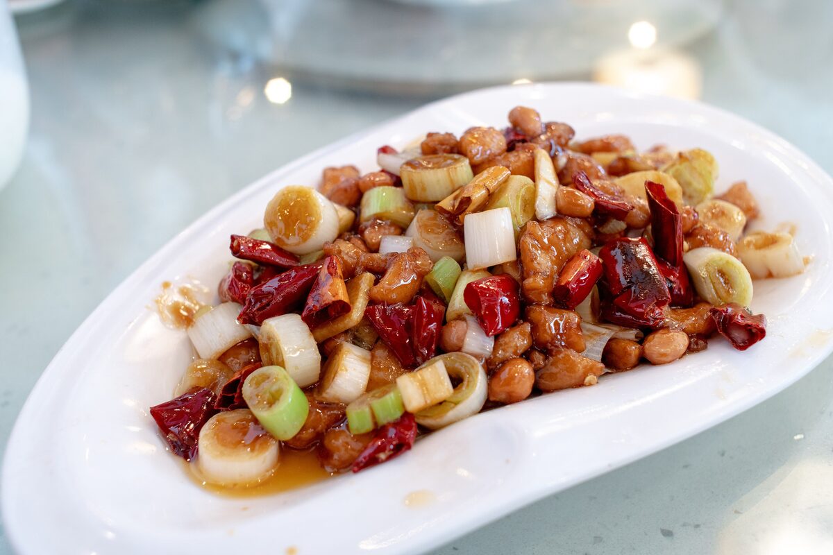 A plate of kung pao chicken with roasted peanuts, dried red chilies and thick scallion pieces