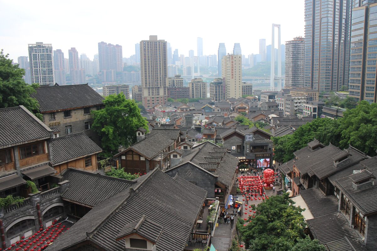 Gray tiled roofs of the old Shibati quarter seen from above, with modern towers rising behind