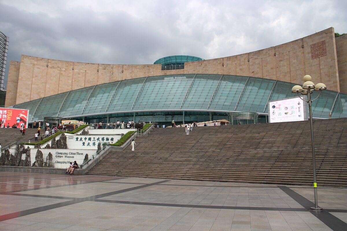 The curved stone wall and glass dome of the Three Gorges Museum above a wide flight of steps