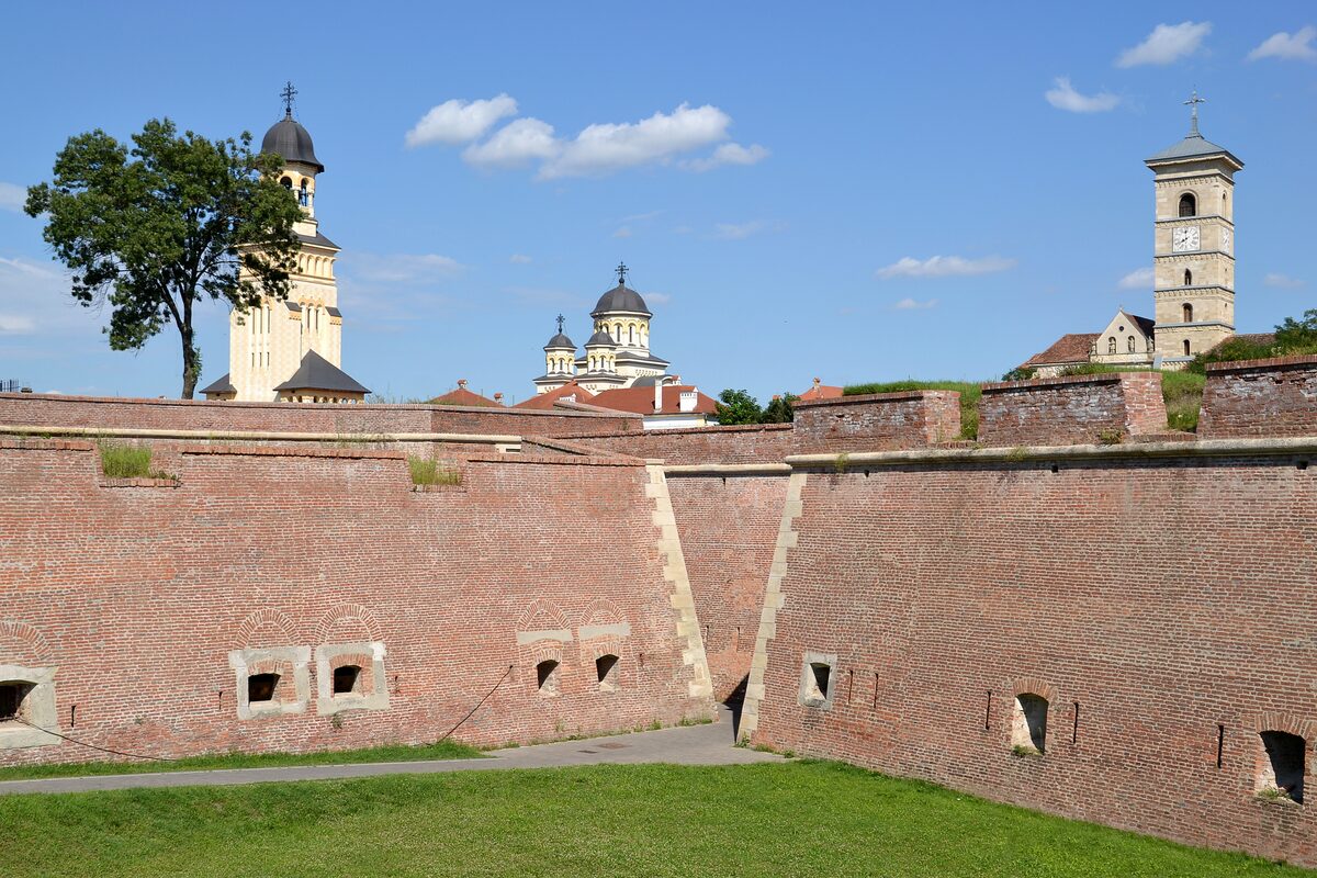 The red-brick walls of the Alba Carolina citadel, with the towers of the Orthodox Coronation Cathedral and St. Michael's Roman Catholic Cathedral rising behind them