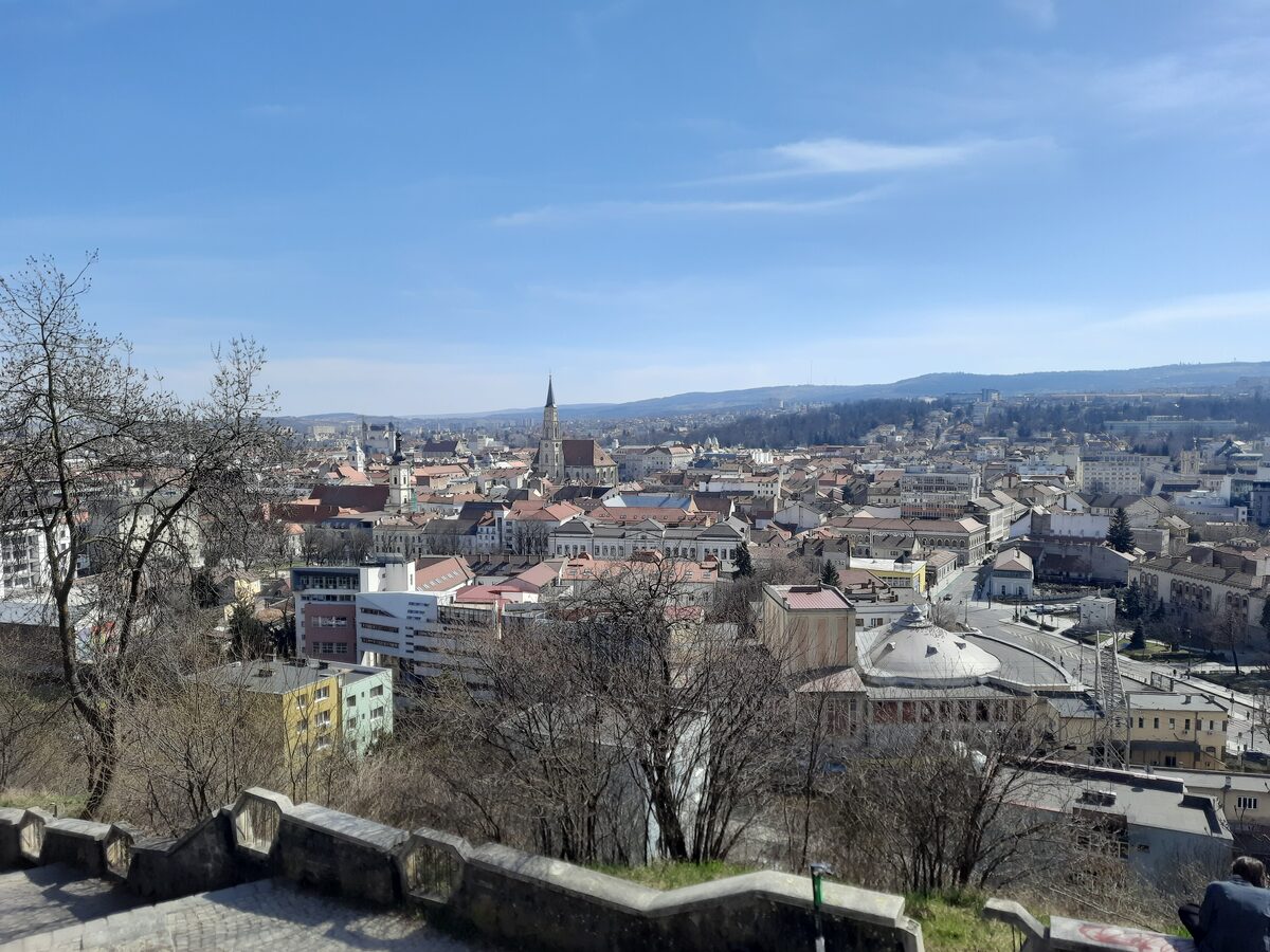 View from the stone parapet on Cetățuia hill over central Cluj in early spring, with St. Michael's spire in the distance