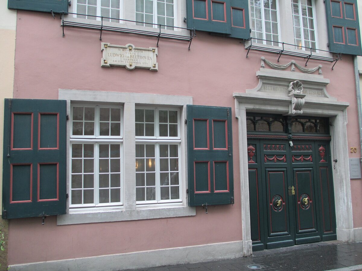 The pink front of the Beethoven-Haus in Bonn with green shutters and a dark green double door