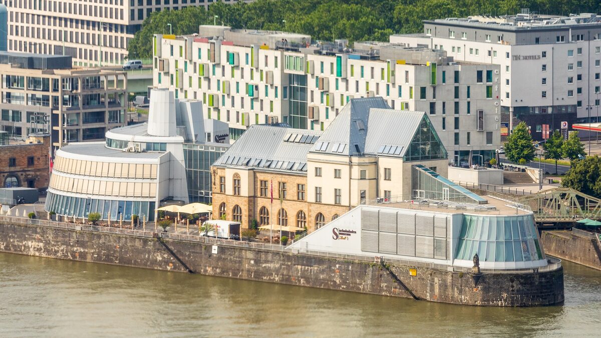 The glass-roofed Chocolate Museum on its peninsula in the Rhine harbor, with old harbor buildings behind