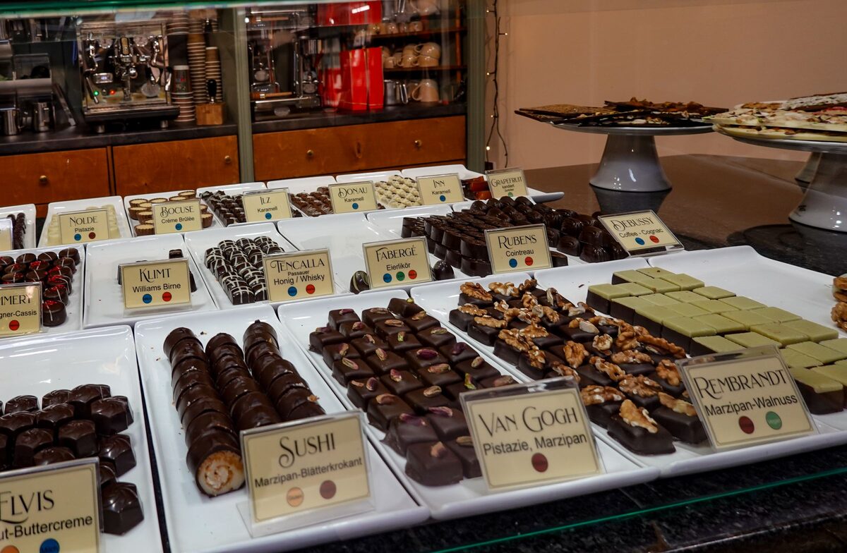 Trays of handmade chocolates and truffles with small price labels at a chocolatier's counter