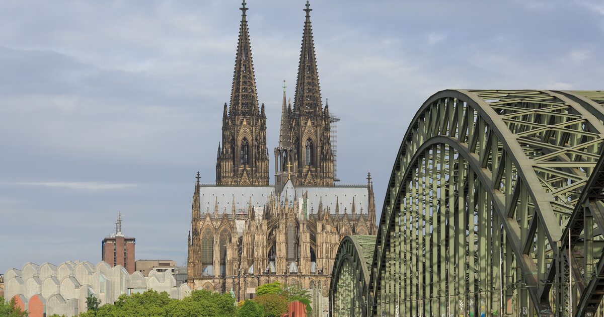 The twin spires of Cologne Cathedral behind the steel arches of the Hohenzollern Bridge