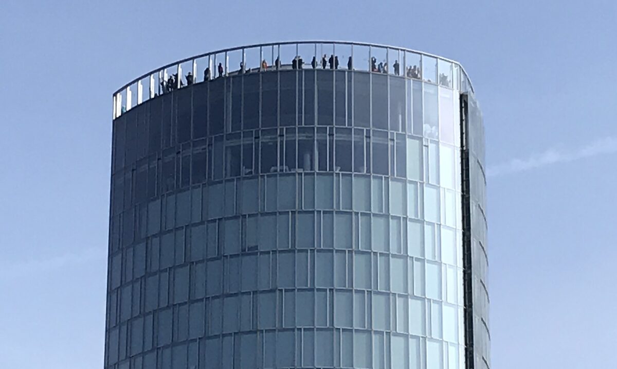 The glass KölnTriangle tower with visitors on the rooftop viewing platform
