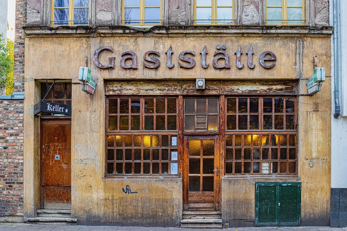 The weathered Gaststätte front of Lommerzheim with small-paned windows and a wooden door