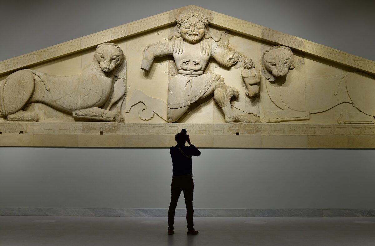 The ancient Gorgon pediment in the Corfu Archaeological Museum: a huge stone Medusa with snakes for a belt, flanked by two crouching lionesses
