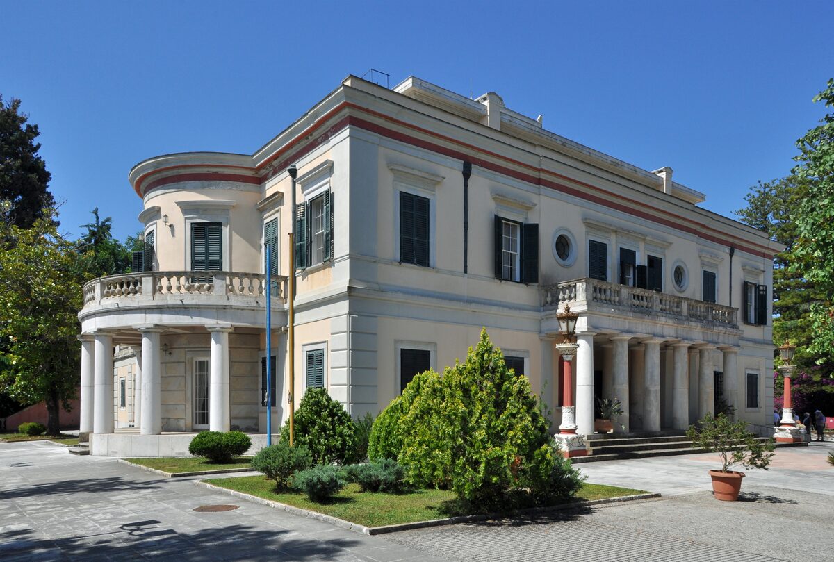 The neoclassical Mon Repos villa with its rounded porch and columns, behind clipped hedges in the park