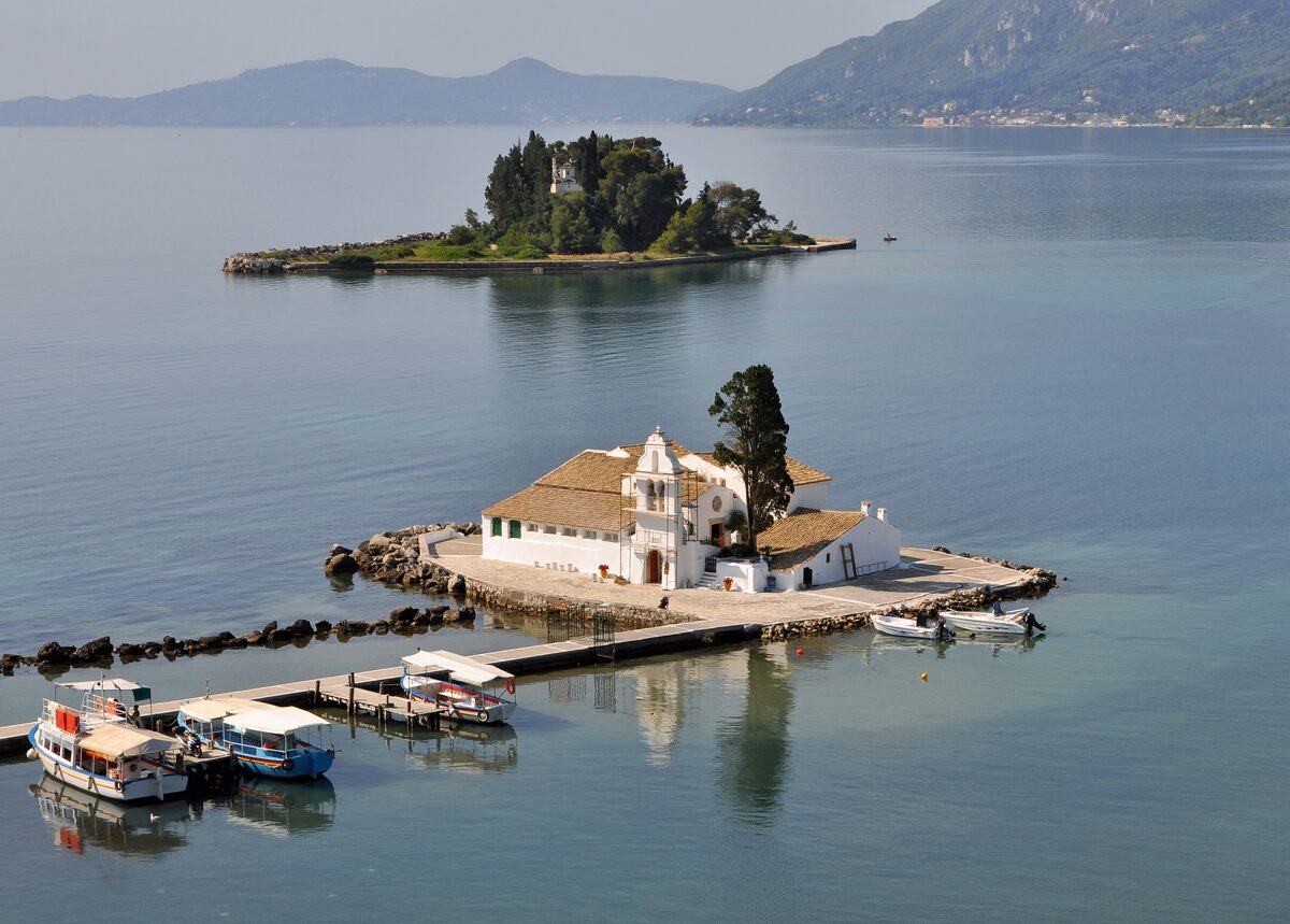 The white Vlacherna monastery on its islet connected by a causeway, with Mouse Island and its chapel behind in a calm lagoon