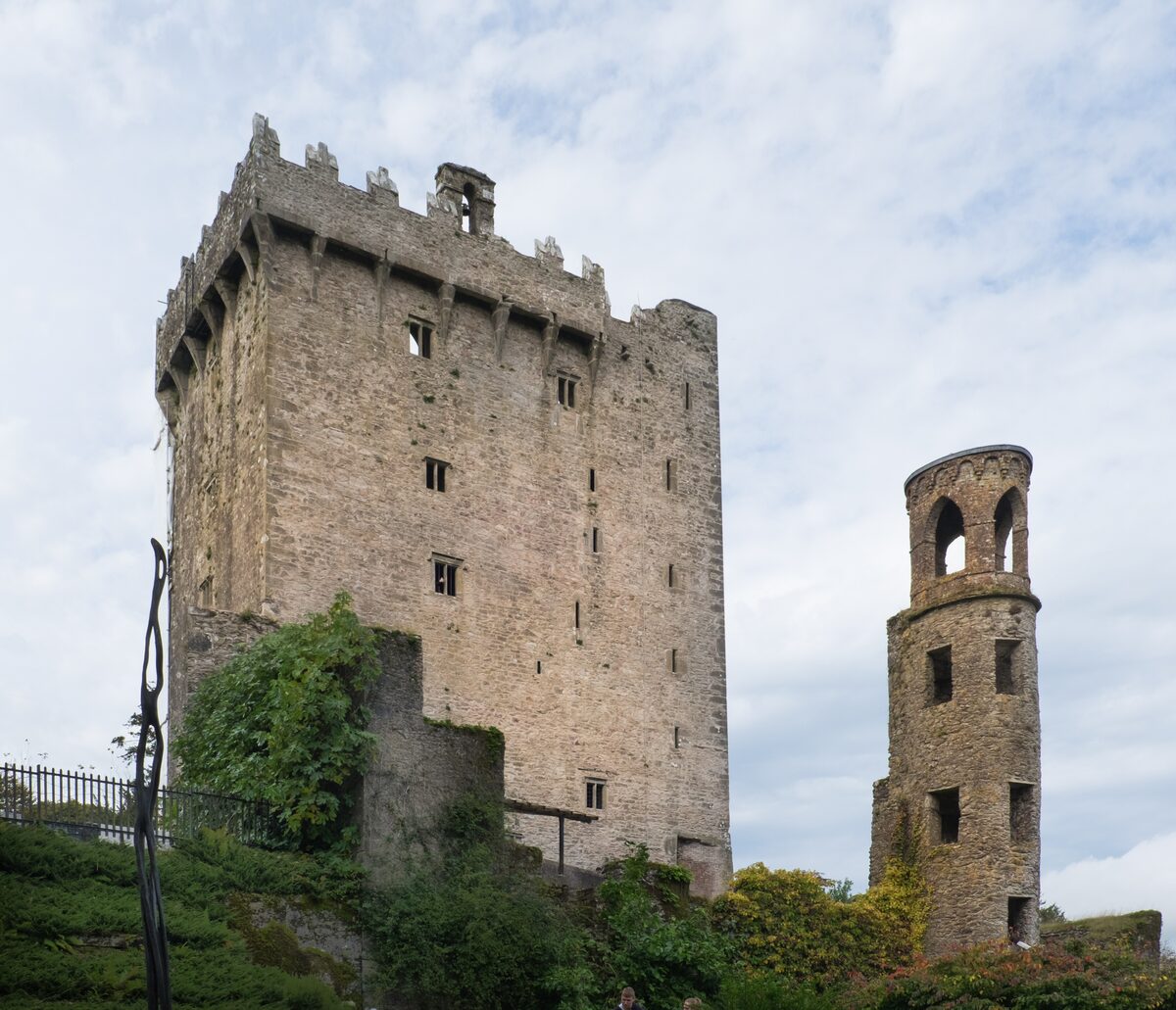 The tall stone keep of Blarney Castle with battlements and a smaller round tower beside it
