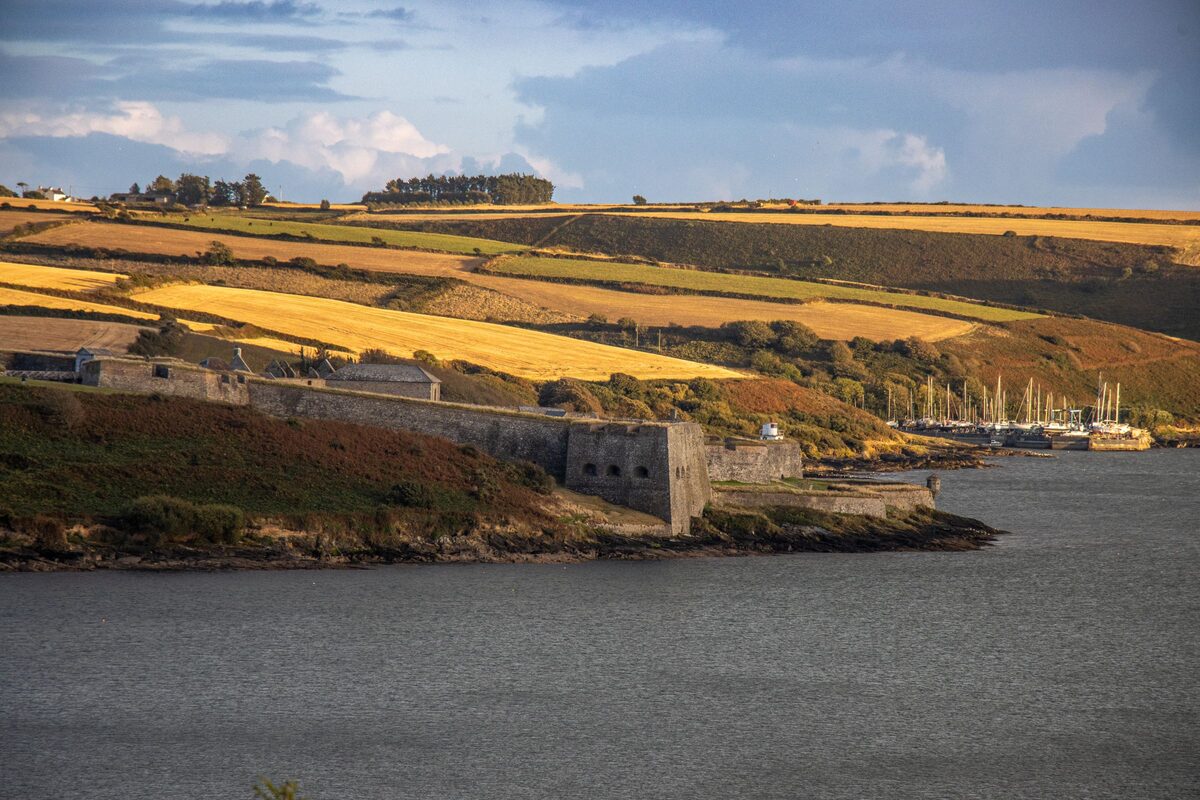 Charles Fort on the shore of Kinsale Harbour, its low star-shaped walls below golden fields and a hill