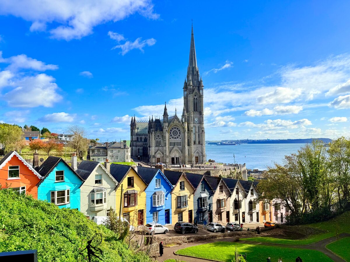 The Deck of Cards in Cobh: a row of brightly painted houses on a steep street below St Colman's Cathedral and Cork Harbour