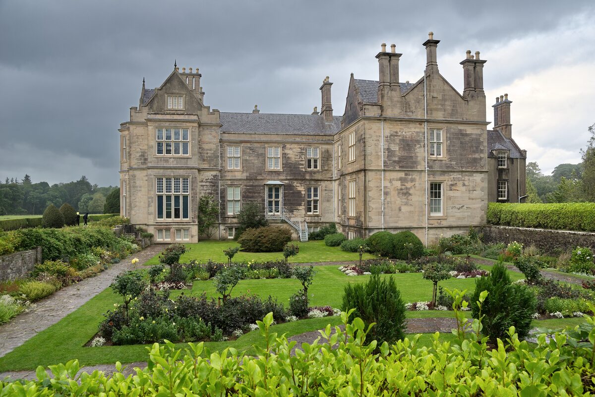 Muckross House in Killarney National Park, a Victorian stone mansion with tall chimneys above formal gardens