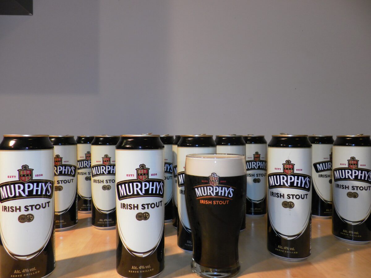 A pint of Murphy's Irish Stout in front of a row of Murphy's cans
