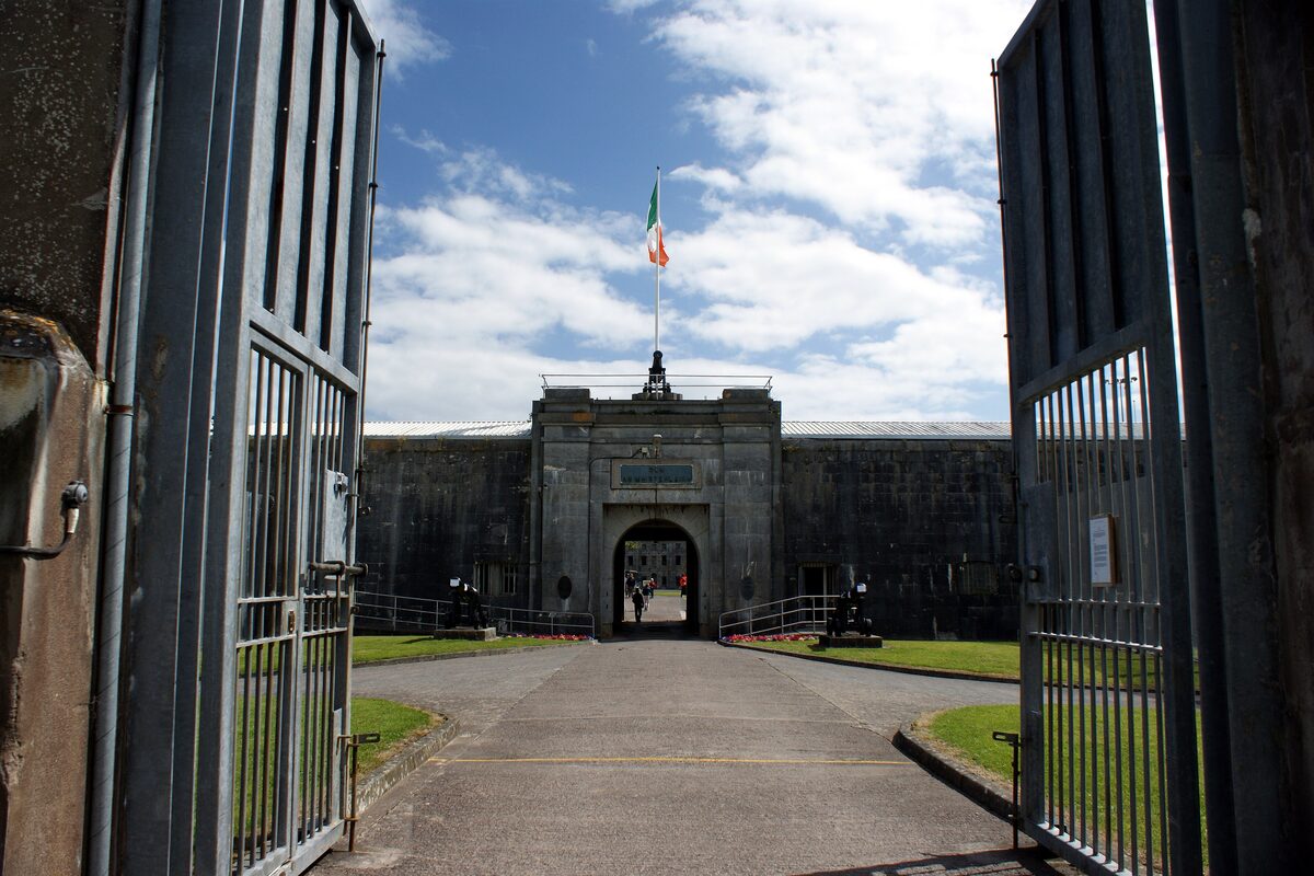 The gate and entrance of Fort Mitchel on Spike Island seen through open iron gates, with the Irish flag above