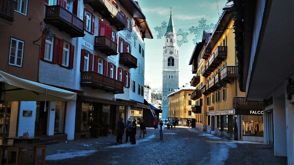 Corso Italia in winter, a snow-dusted pedestrian street with shopfronts and the Basilica bell tower at the end