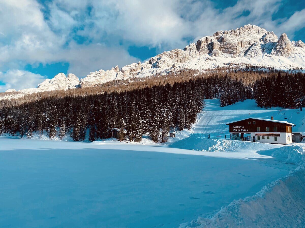 The frozen, snow-covered Lake Misurina with the Col de Varda chairlift station at the edge of the pine forest and snowy peaks above
