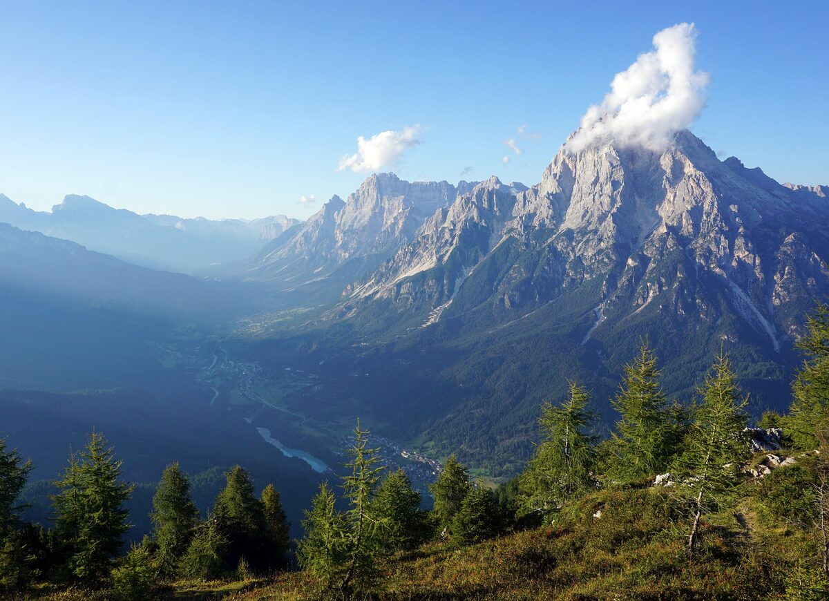 Monte Antelao rising above the valley of San Vito di Cadore, with larch trees in the foreground and a cloud on the summit