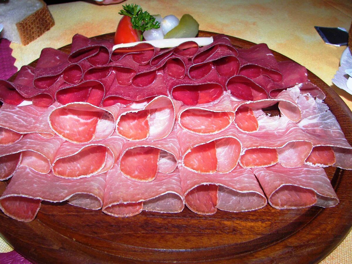 Thin slices of air-dried Bündnerfleisch fanned out on a round wooden board