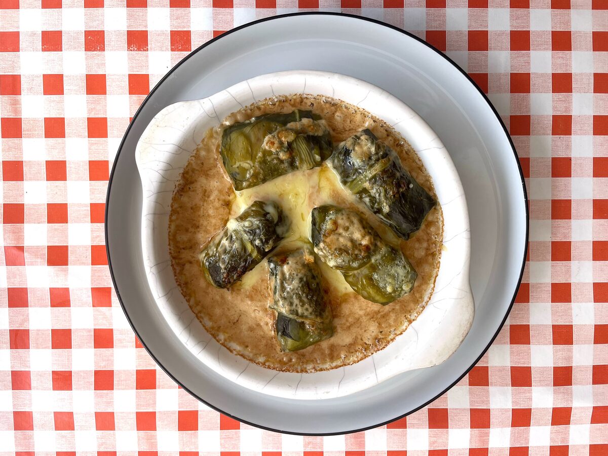 Capuns, chard-wrapped dough rolls under melted cheese in a white dish on a checked cloth
