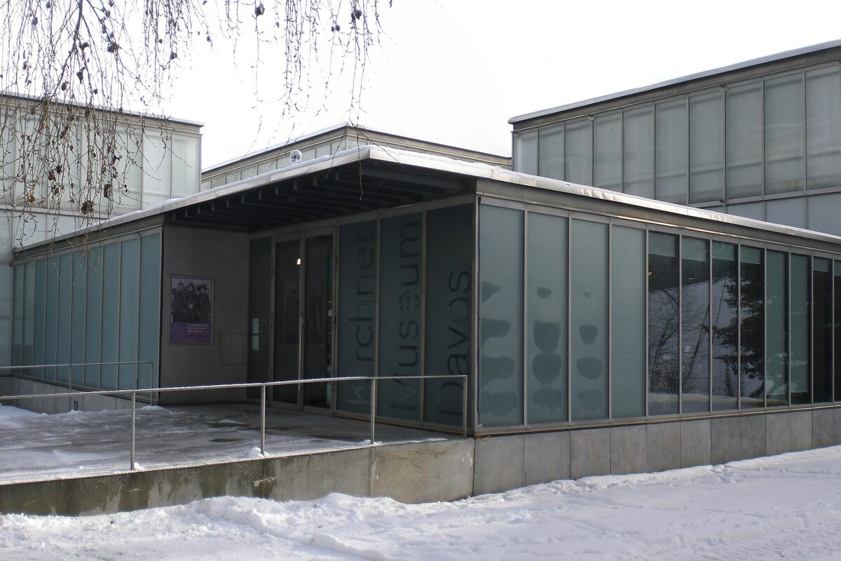 The glass entrance of the Kirchner Museum in Davos on a snowy day, with the museum's name on the glass