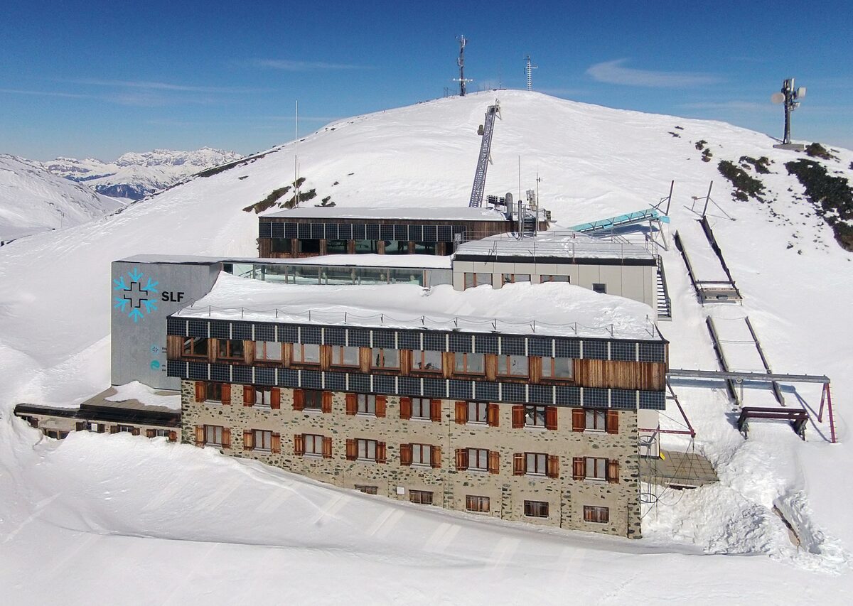 The former main building of the SLF snow research institute on the Weissfluhjoch, buried in snow under a clear sky