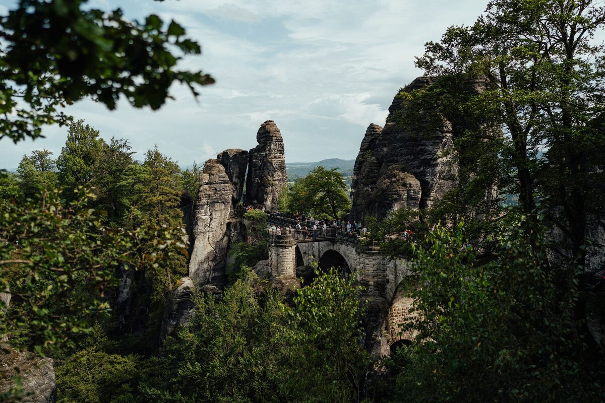 The stone arches of the Basteibrücke between sandstone pinnacles, framed by trees